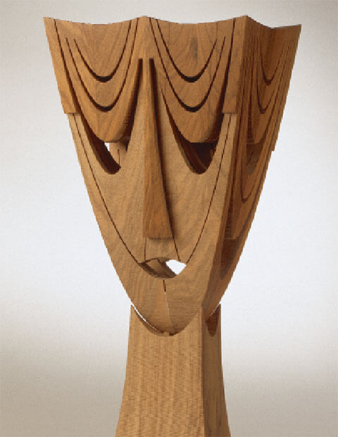 Parabolischer Kopf mit zwei Gesichtern, 1993, Nussbaumholz, 42 x 26 x 26 cm. Parabolische Umrisse ergeben den über sich hinaus strebenden Kopf